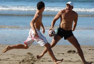  Teen and father face each other in a game of touch. Campbell's Bay, July 2008.